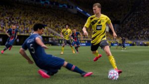 Football match with a defender sliding toward an opposing attacker dribbling the ball inside a crowded stadium